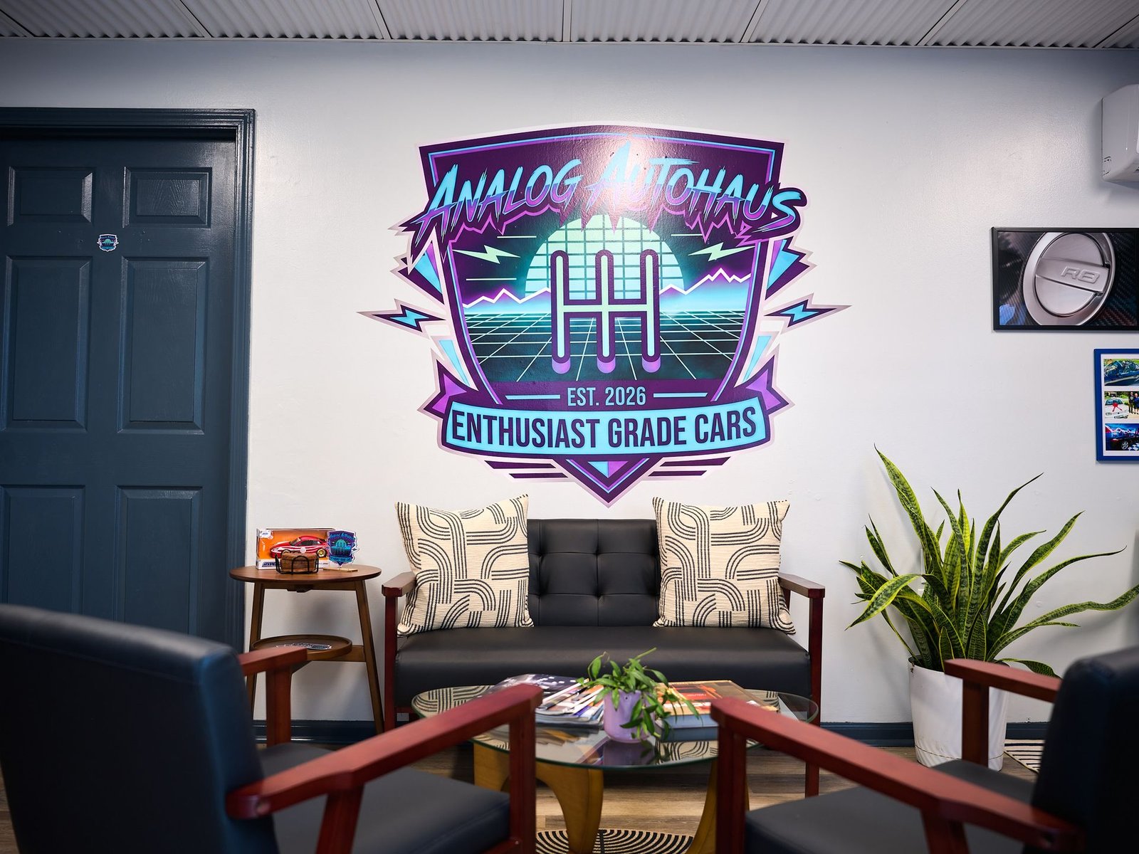 Analog Autohaus Enthusiast Grade Cars logo wall above the sofa in the Office & Customer Lounge, Sarasota
